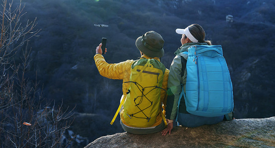 青年登山者伴侣坐在岩石上自拍
