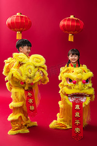 春节黄色灯笼摄影照片_欢乐的男孩女孩舞狮庆祝新年