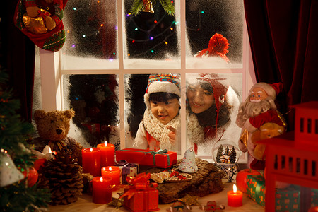 可爱礼物盒子摄影照片_母女透过窗户看圣诞节礼物