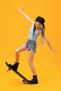 橙色动感背景摄影照片_个性年轻女孩玩滑板