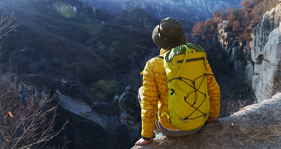 山顶云摄影照片_青年登山者坐在山顶俯瞰