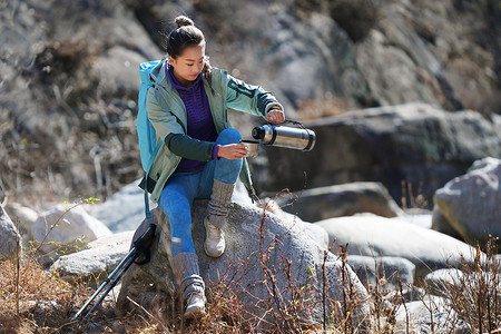 徒步旅行的青年女人坐在石头上休息