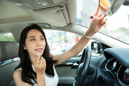 漂亮的青年女人对着后视镜化妆