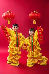 春节黄色灯笼摄影照片_欢乐的男孩女孩舞狮庆祝新年