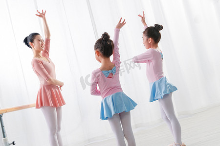 舞蹈女孩们摄影照片_年轻舞蹈老师教小女孩们跳舞