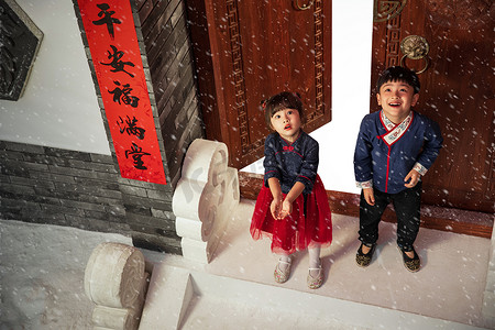 喜庆中过年摄影照片_雪中在门口玩耍的快乐男孩女孩