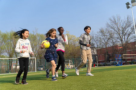 外国人穿球衣摄影照片_可爱的小学生们在草地上玩耍