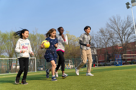 球场男生摄影照片_可爱的小学生们在草地上玩耍