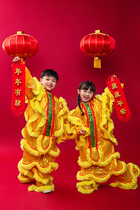 春节黄色灯笼摄影照片_欢乐的男孩女孩舞狮庆祝新年