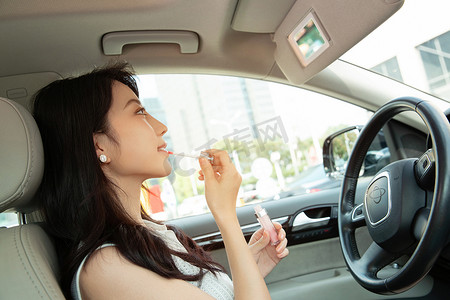 青年女人坐在车里化妆