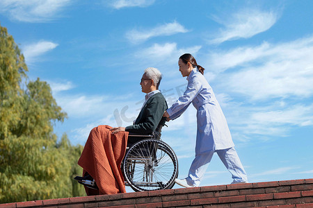 护士病人摄影照片_护士推着坐在轮椅上的老人散步