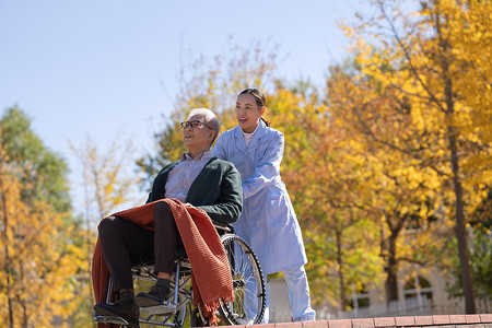 老年人摄影照片_护士推着坐在轮椅上的老人散步