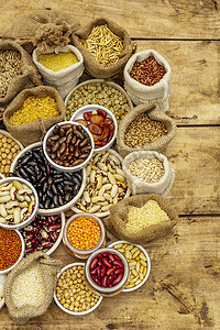 对不同类型的豆类和谷类谷物进行分类。一组健康生活所不可缺少的蛋白质来源。旧木板背景图，顶视图