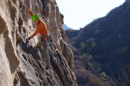 极限攀岩摄影照片_青年男人在悬崖峭壁上攀岩