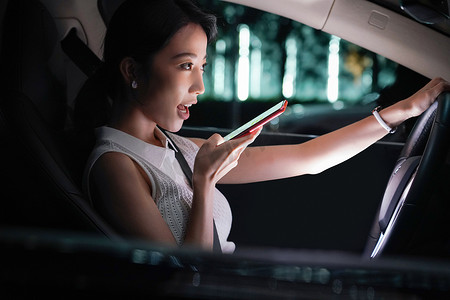 驾驶汽车的青年女人使用手机语音聊天