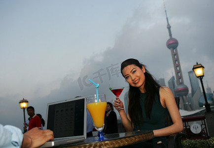 傍晚外滩黄浦江边一位女青年坐在桌旁端着饮料