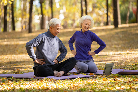 视频秋天摄影照片_户外观看平板电脑练瑜伽的老年夫妇