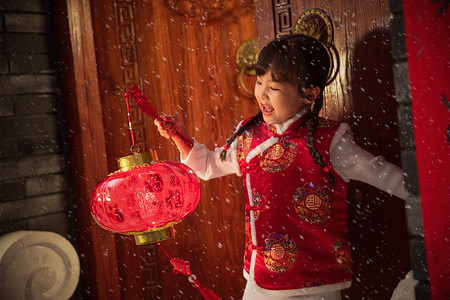 手提灯笼的人摄影照片_雪中小女孩手提红灯笼玩耍