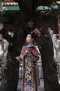 穿清宫服的青年女人站在古树下