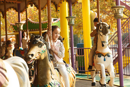 骑木马的男孩摄影照片_男孩女孩在玩旋转木马