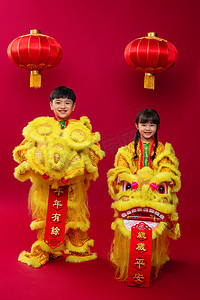 春节黄色灯笼摄影照片_欢乐的男孩女孩舞狮庆祝新年