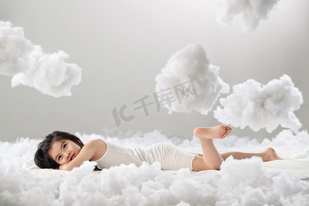 可爱的小女孩躺在云朵上