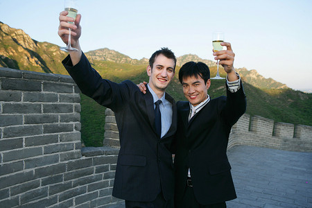 两位中外商务人士在长城上举杯庆贺