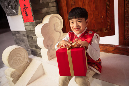 开着大门摄影照片_可爱的小男孩抱着礼品盒