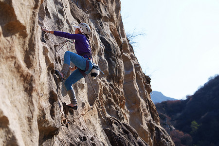 极限攀岩摄影照片_青年女人在悬崖峭壁上攀岩