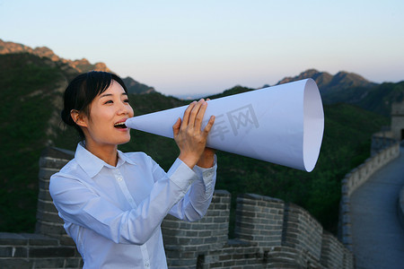 女商务人士在长城上用喇叭讲话