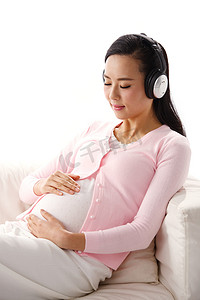听音乐背景摄影照片_孕妇坐在沙发上听音乐