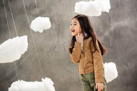 乐趣设计摄影照片_快乐小女孩在云朵间玩耍