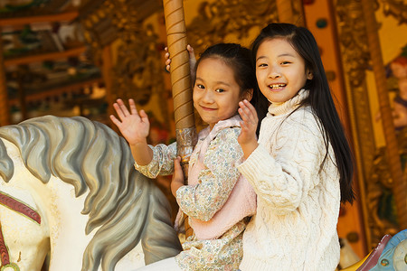 可爱设施摄影照片_两个小女孩在玩旋转木马