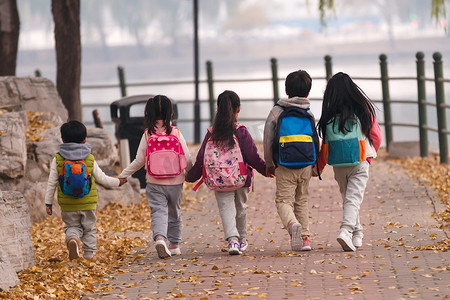 秋天的落叶摄影照片_小学生在放学的路上