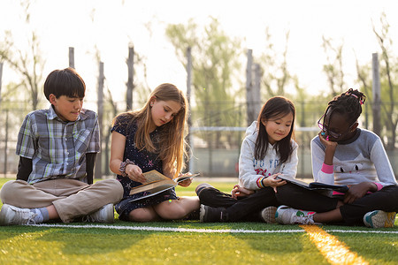 外国人穿球衣摄影照片_国际学校学生坐在草地上看书