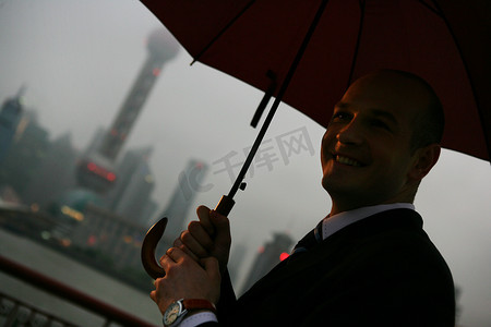 阴雨天外滩黄浦江边一位外国商务人士拿伞微笑