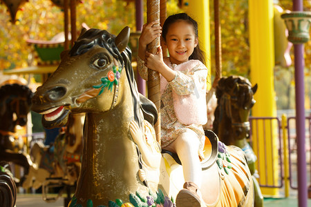 游乐园设施摄影照片_一个小女孩在玩旋转木马
