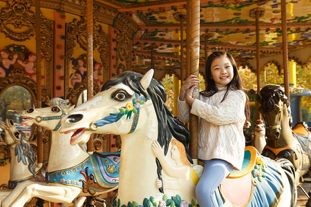 可爱设施摄影照片_一个小女孩在玩旋转木马