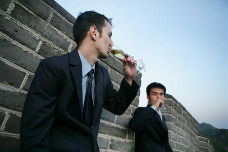 两位中外商务人士在长城上饮酒