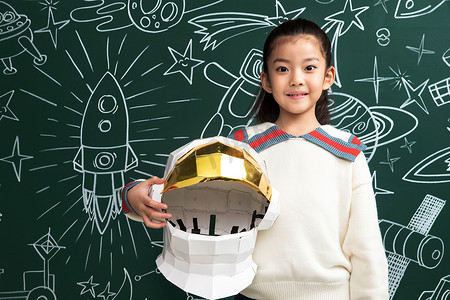 抱着航天员头盔的小女孩站在黑板前