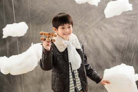 木质飞机模型摄影照片_拿着玩具飞机的快乐男孩