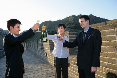 三位中外商务人士在长城上举杯庆贺