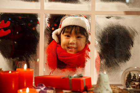 小女孩透过窗户看圣诞节礼物