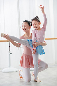 两腿分开摄影照片_年轻舞蹈老师教小女孩跳舞