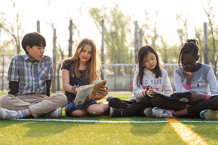 国际学校学生坐在草地上看书