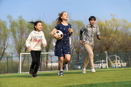 球场男生摄影照片_可爱的小学生们在草地上玩耍