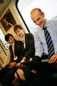 上海城铁车厢内三位中外商务人士使用笔记本电脑和MP3
