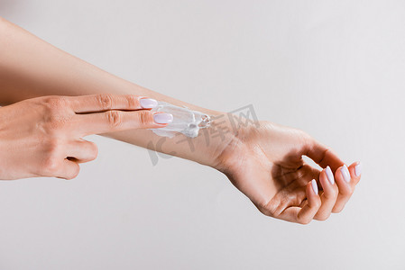 妇女在手臂上涂上用灰色隔离的护手霜的剪影