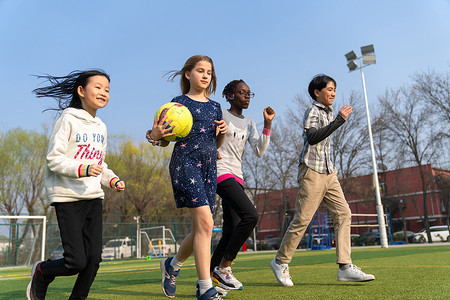 学生操场玩耍摄影照片_可爱的小学生们在草地上玩耍