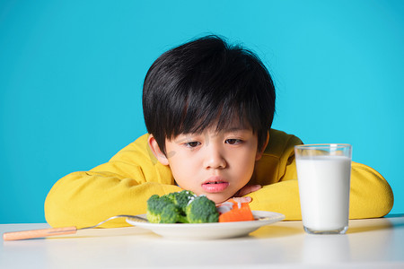 的烦恼摄影照片_盯着蔬菜发愁的小男孩